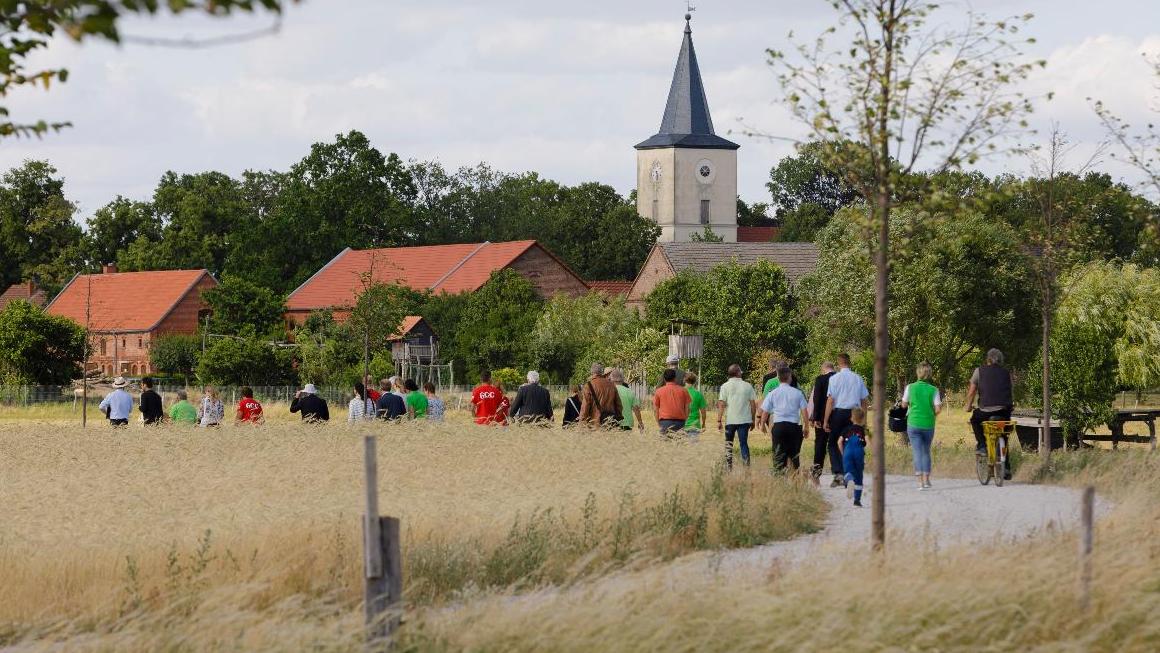 Eine Gruppe Menschen geht durch ein Dorf.