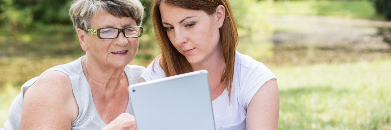 A young woman shows an older woman something on a tablet