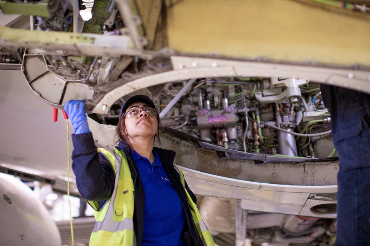 Person in yellow vest inspecting airplane tires