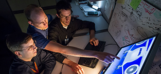 People working at computer screen with image of aircraft on it