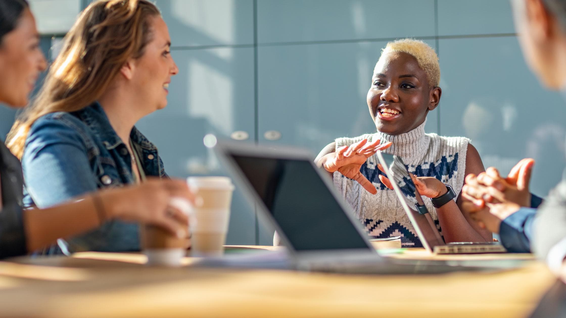 Health, Safety & Well-being - Cheerful woman in business meeting with colleagues