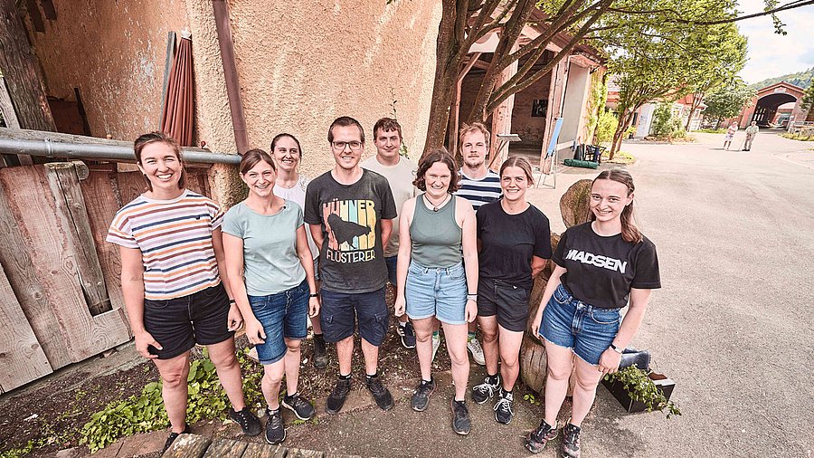 Gruppenbild von neun jungen Menschen, die nebeneinander stehen.