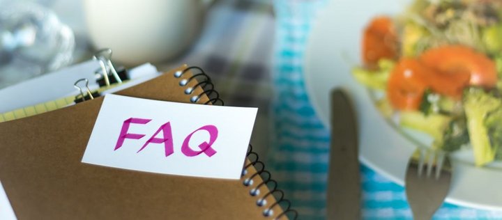 Teller mit Essen daneben Ringbuch mit Schild FAQ