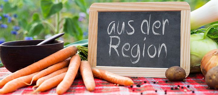 frisches Gemüse liegt auf einem Tisch mit einer Tafel auf der "aus der Region" steht