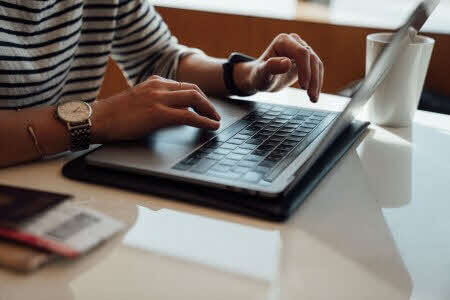 Hands typing on a laptop keyboard