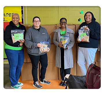 Square shaped photo of four women holding community donation items