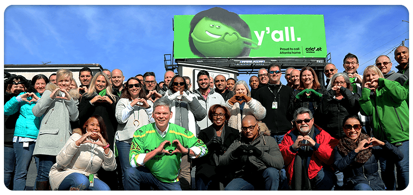 Large group photo in front of Cricket billboard that says Y’all