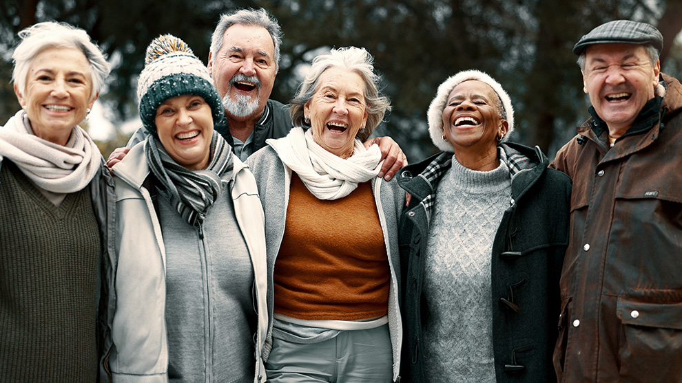 Gruppe älterer Menschen, die sich umarmen und lachen | Quelle: © Clement C/peopleimages.com/stock.adobe.com