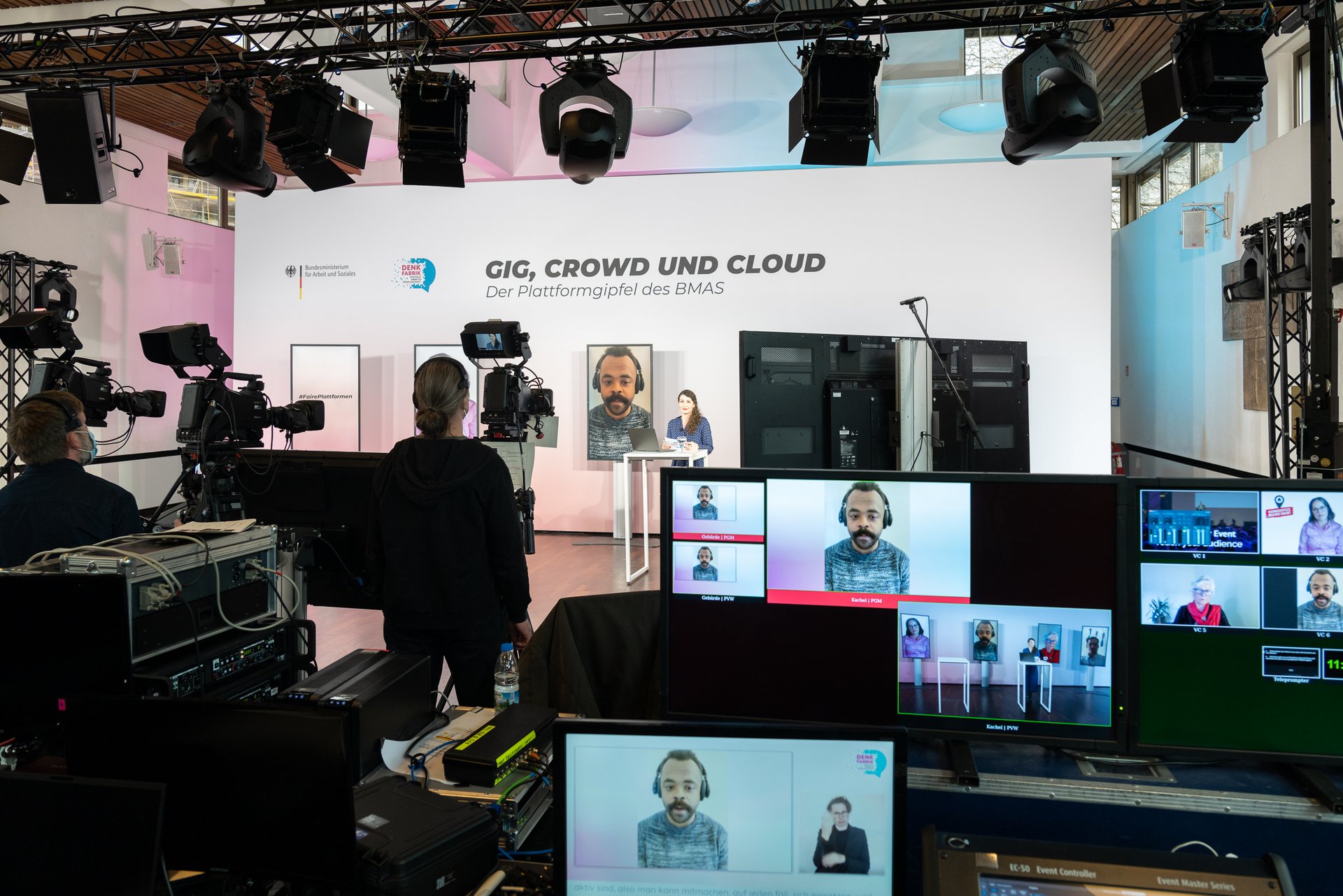 Ein zugeschalteter Mann ist auf den Monitoren der Veranstaltungstechnik und auf einem Monitor auf der Bühne zu sehen.