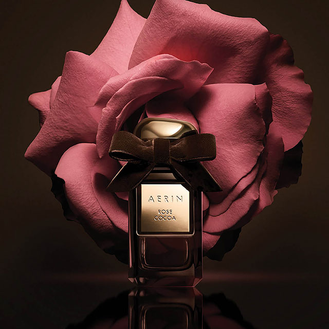 New Aerin Rose Cocoa fragrance on a dark brown background with rose petals