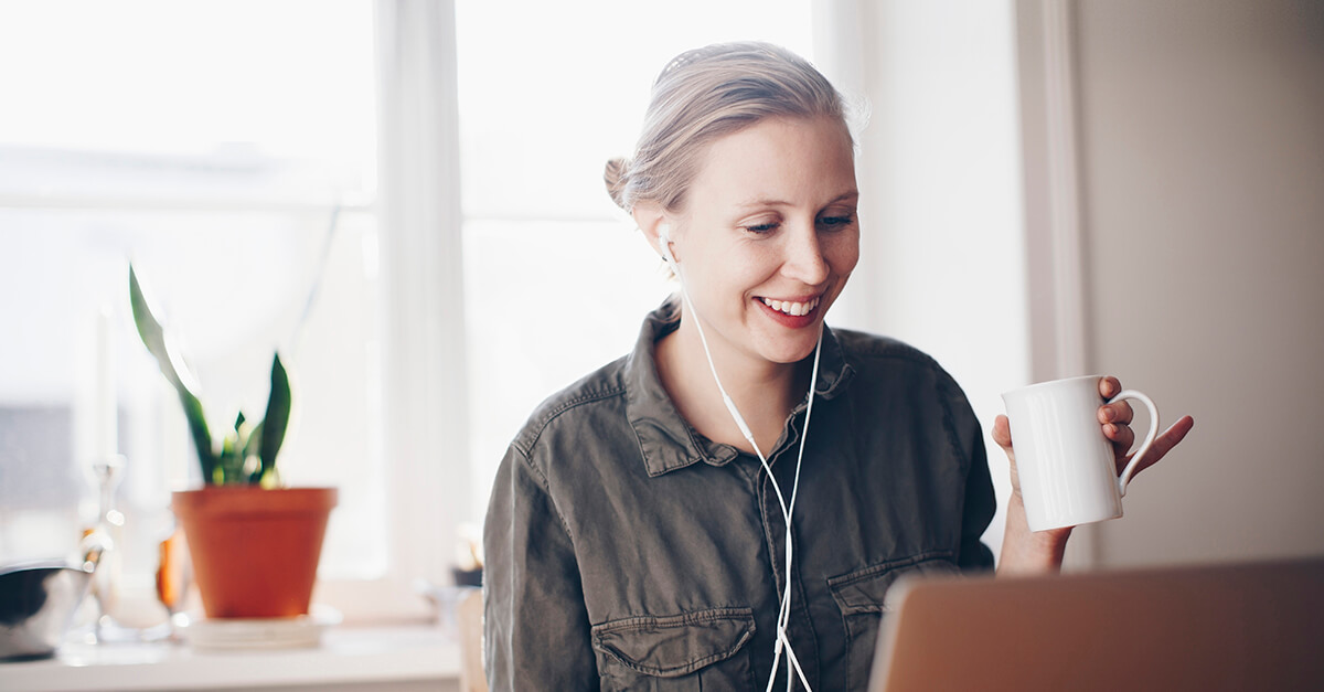 Woman sitting at her laptop with a hot drink