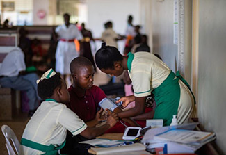 The photo on this page is set in a health care facility and shows two female professionals,wearing pale yellow and green uniform