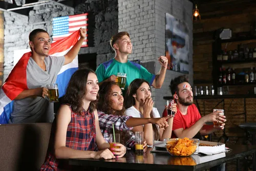 Five France fans with flags and face paints cheer on their team with drinks and snacks