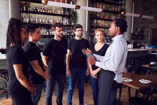 A restaurant manager briefs floor staff before service begins