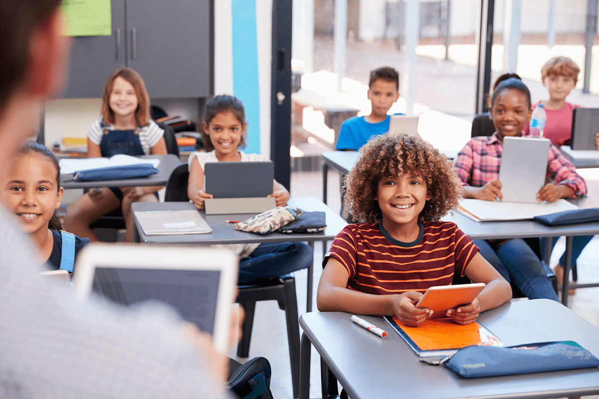 Teacher instructing a classroom of students who work on electronic devices