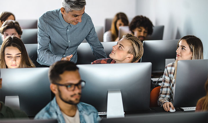 Instructeur parlant à des étudiants dans une salle informatique