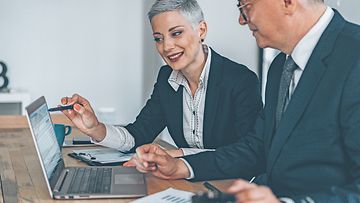 Businessman and business woman working together at the office using laptop and documents