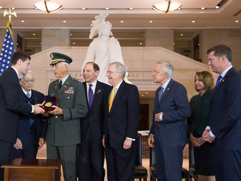 Paul Ryan presenting a medal to Colonel Manuel F. Siverio Sr. as others are watching