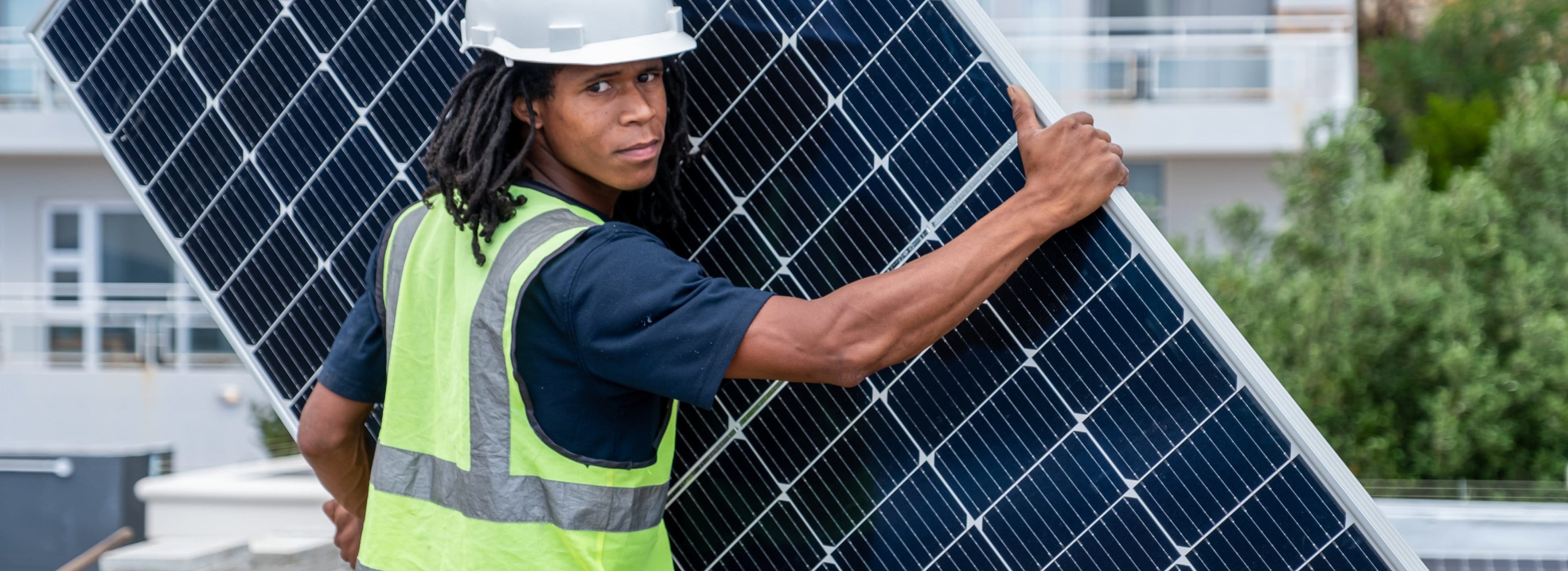 Trabajador transportando un gran panel solar para su instalación.