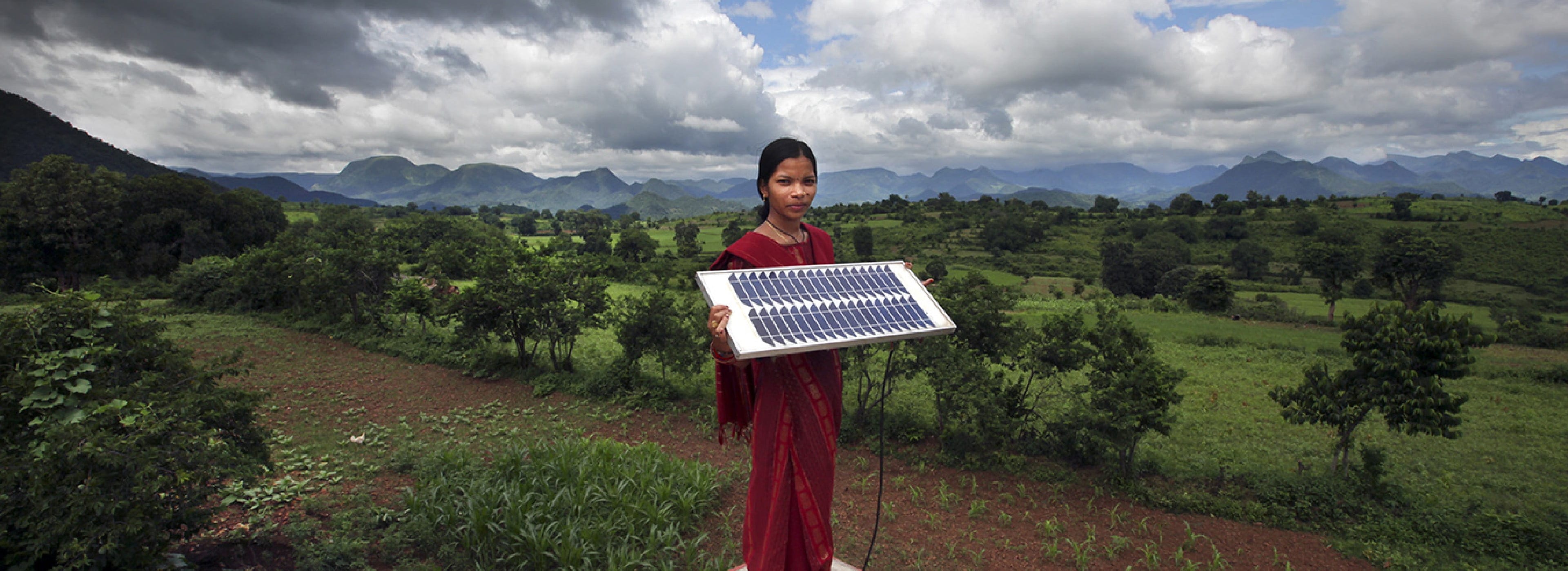 Niña sosteniendo un panel solar en un entorno rural.