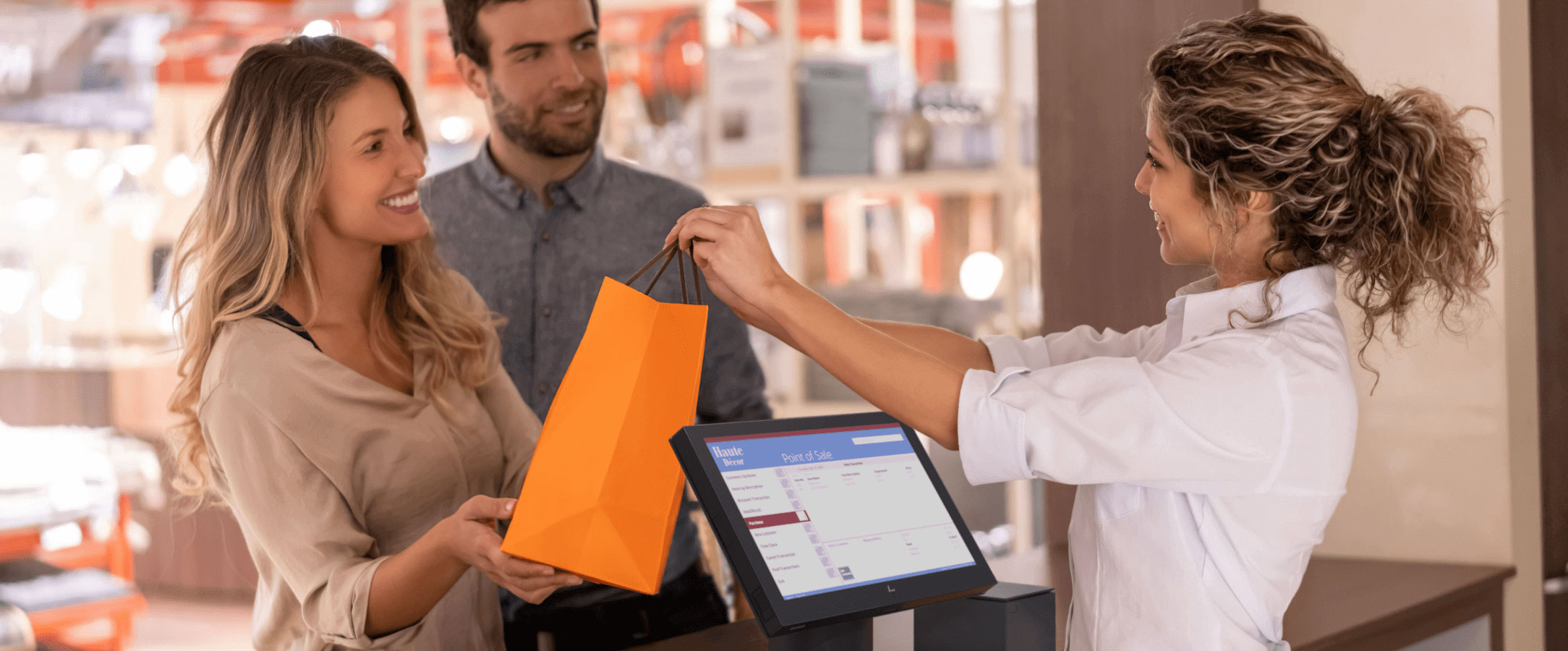 Couple receiving a shopping bag from cashier, an HP Engage point of sale system is at the checkout counter