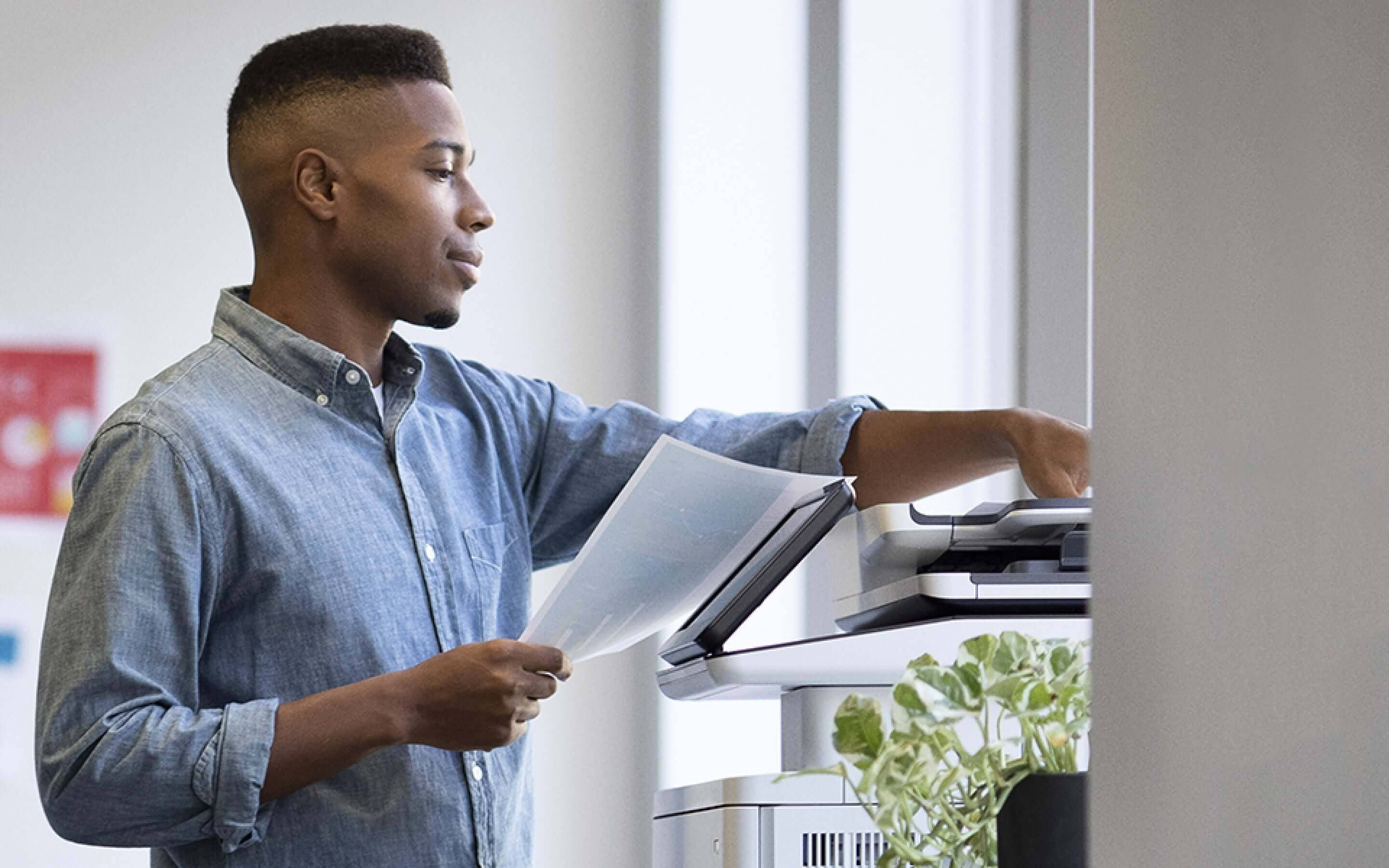 Homme debout devant une imprimante HP LaserJet avec des documents imprimés en main