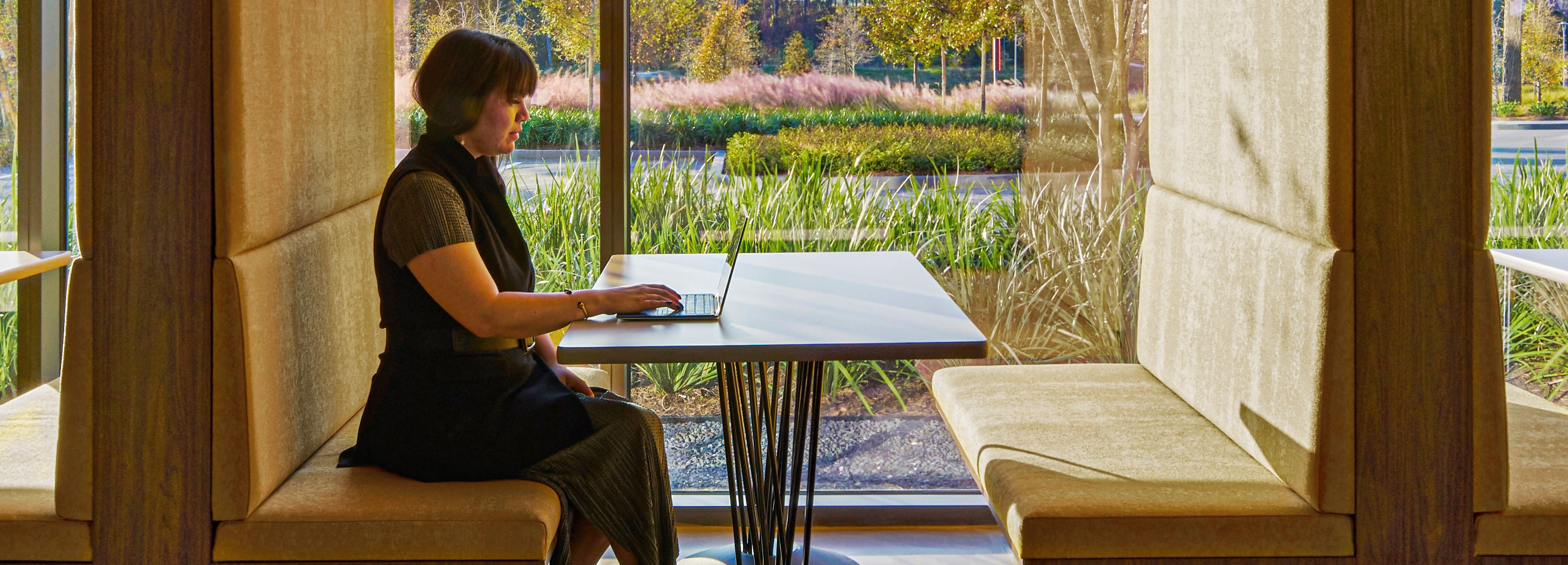 Une femme assise à une table avec un ordinateur portable HP devant un paysage naturel