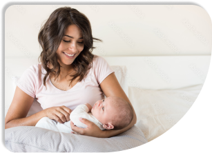 A mother is sitting in a bed while holding a child.