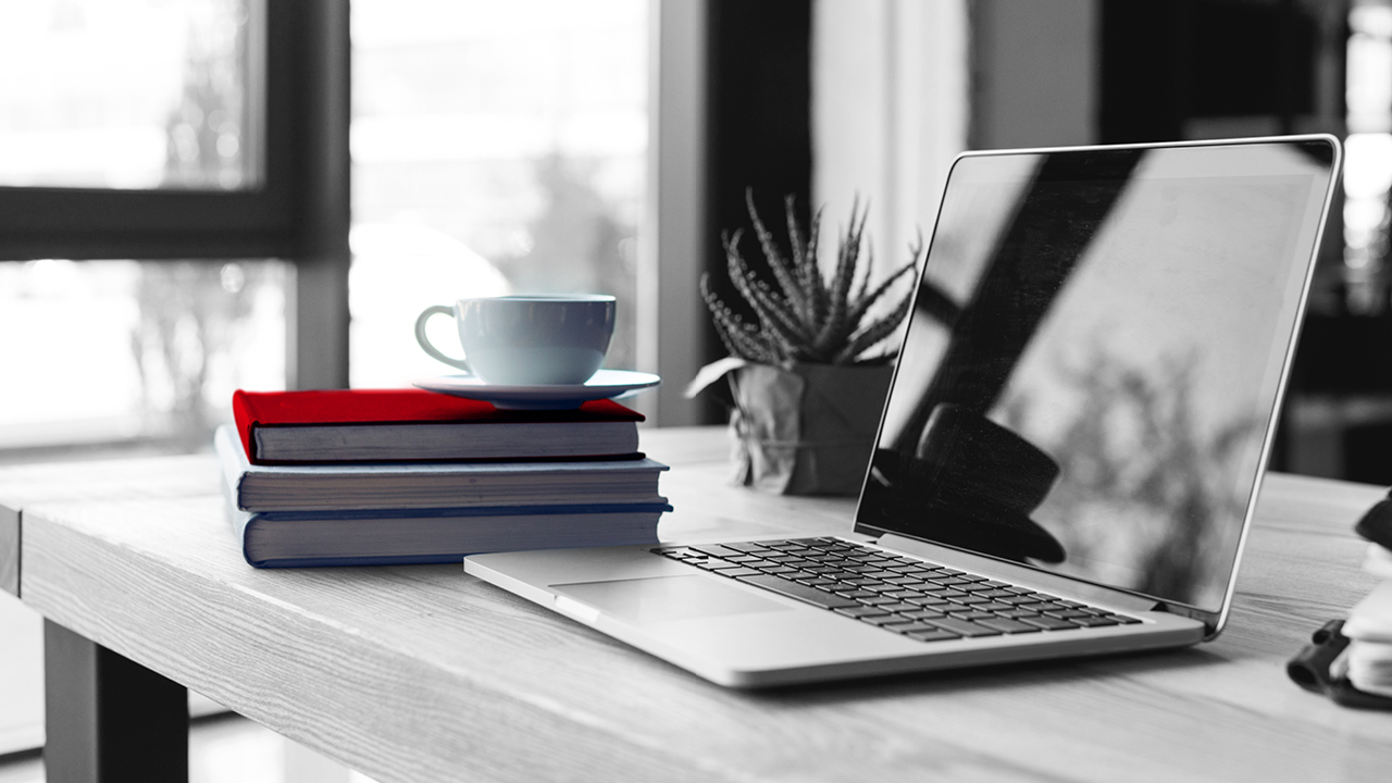 A desk with books, laptop, personal notebook, a plants and a cup of tea; image used for HSBC Australia online banking.