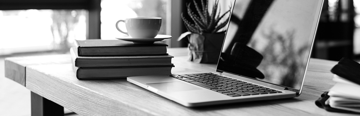 A desk with books, laptop, personal notebook, a plants and a cup of tea; image used for HSBC Australia online banking.