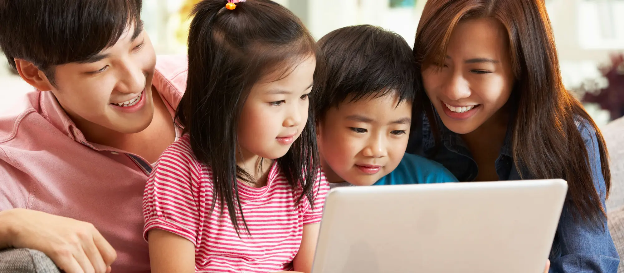 Cute little Asian boy sit with mother using notebook computer.