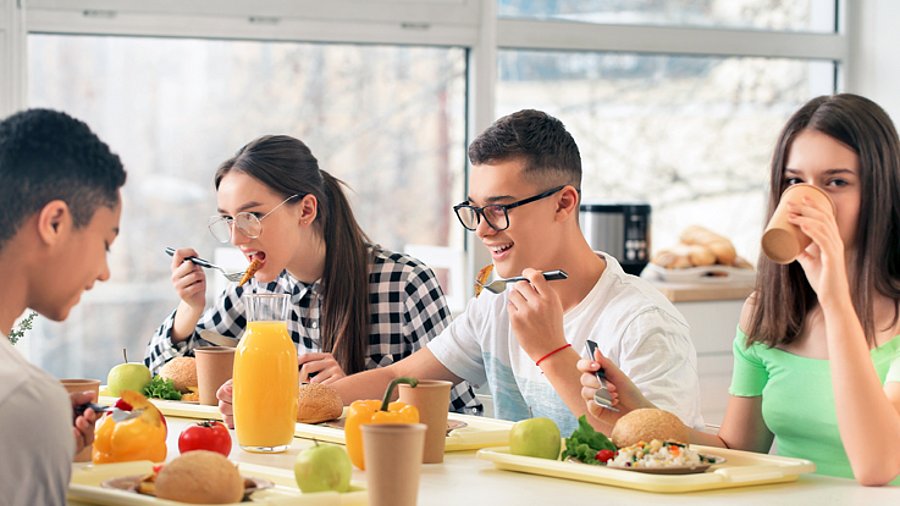 Vier Jugendliche beim Essen in einer Schulkantine