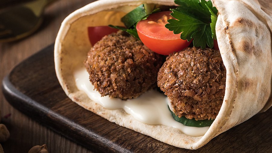 Falafel-Sandwich auf einem dunklen Holzbrett