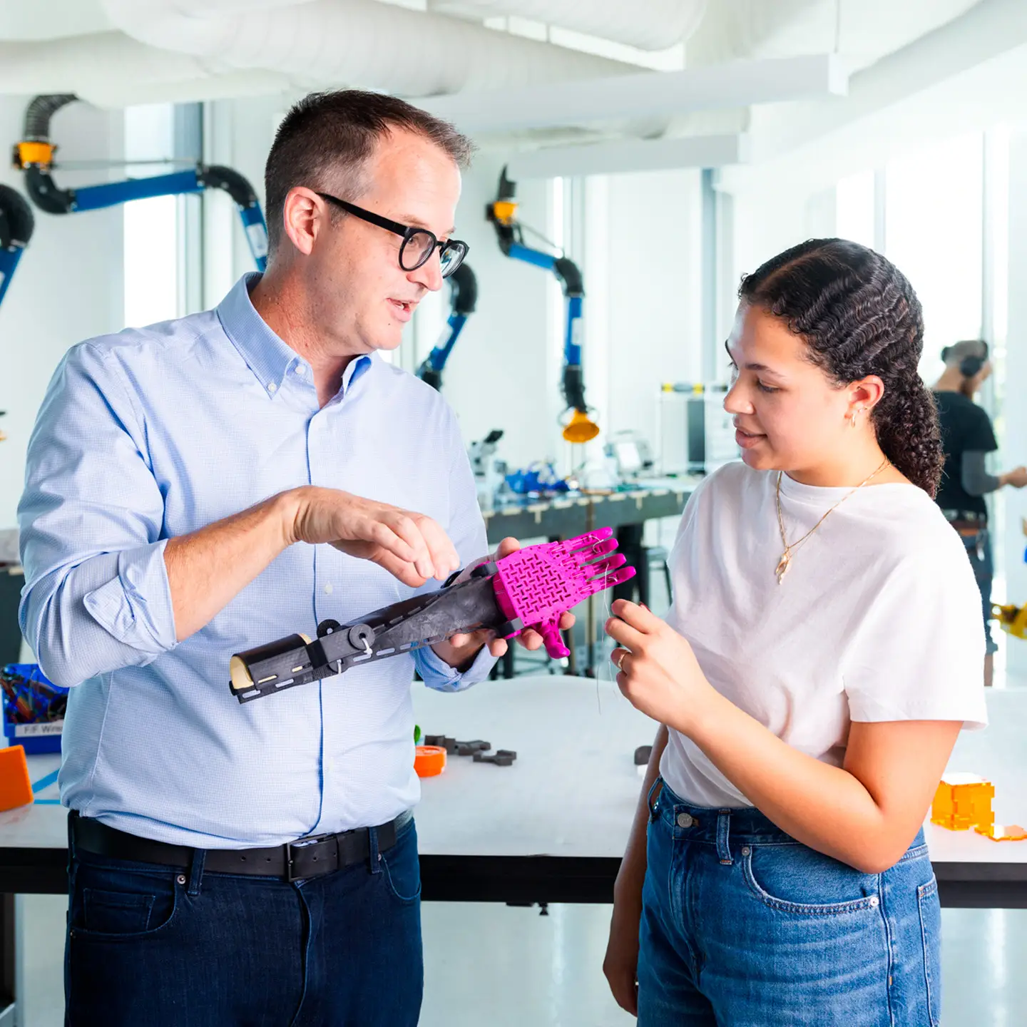 John Racek demonstrates a prosthetic arm to a female student at the Luddy SICE Protolabs.