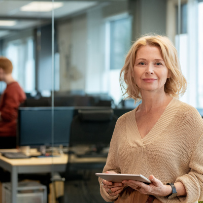 Mitarbeiterin mit Tablet in der Hand stehend in einem Büro.