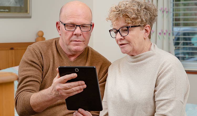 A couple reads information on a tablet. 