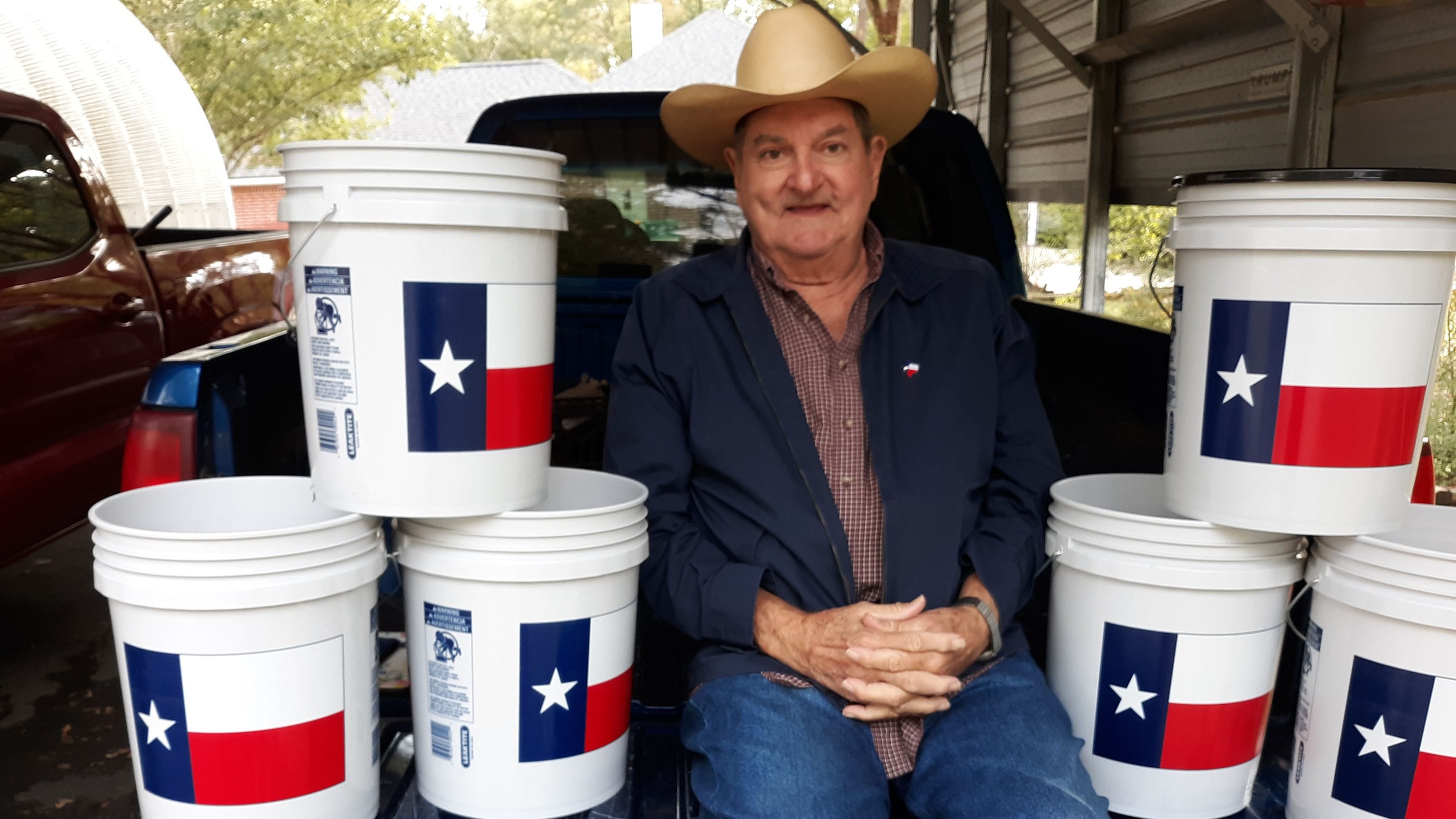 Nolan Maxie sitting next to white buckets with the Texas state flag on them.