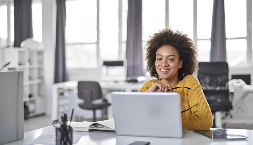 nwg photo smiling woman in yellow jumper looking at laptop