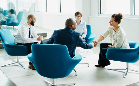 Photo of four people sitting in an office and shaking hands