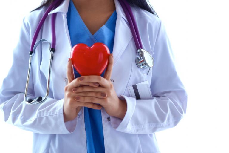 Doctor with stethoscope holding heart, isolated on white background