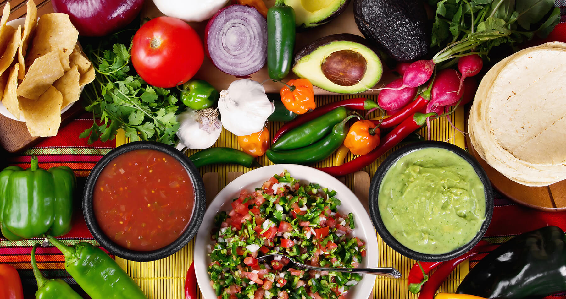 Photo: A table full of fresh tomatoes, onions, garlic, avocado, a variety of peppers, cilantro, radishes, guacamole, salsa and tortillas