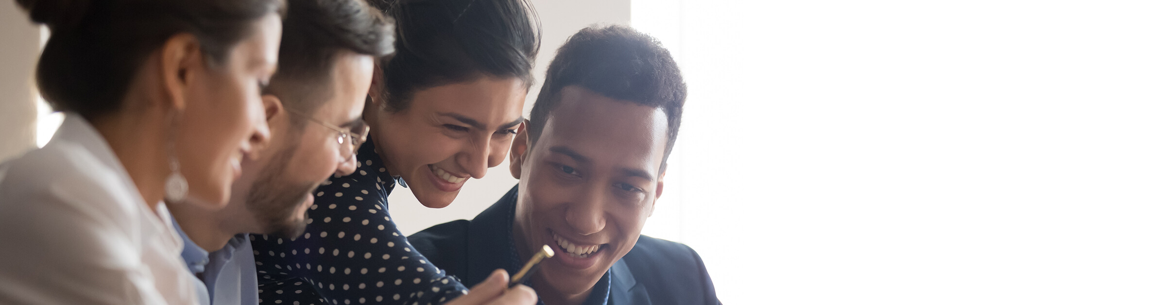 2 women and 2 men of different races and ethnicities look at something on a computer screen