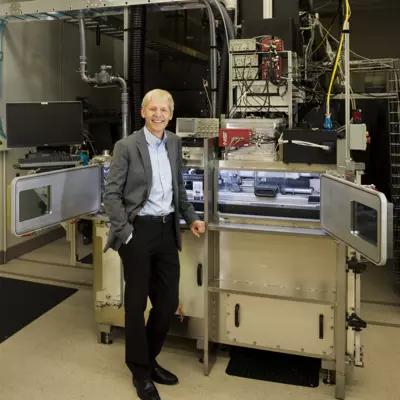 NIST Chief Metrologist Jim Olthoff stands in front of equipment in a lab. 