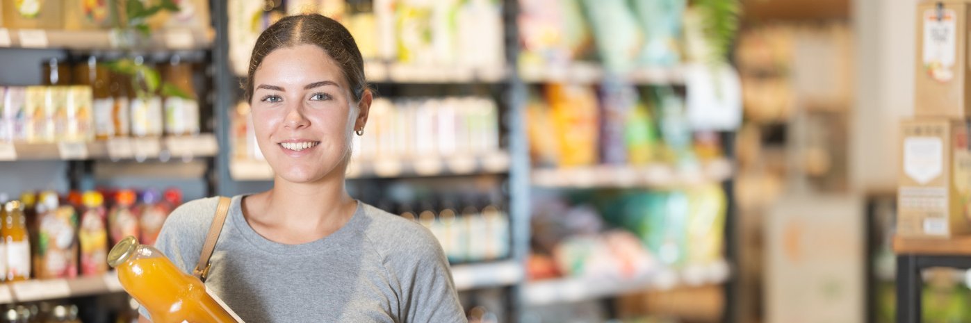 Junge Frau kauft Saft im Laden. 