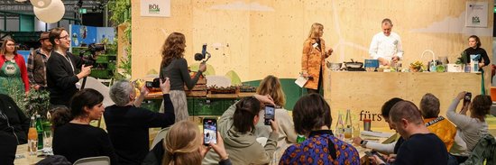 Bühne am Messestand, Publikum im Vordergrund.