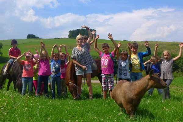 Menschen mit Tieren auf einer Weide.