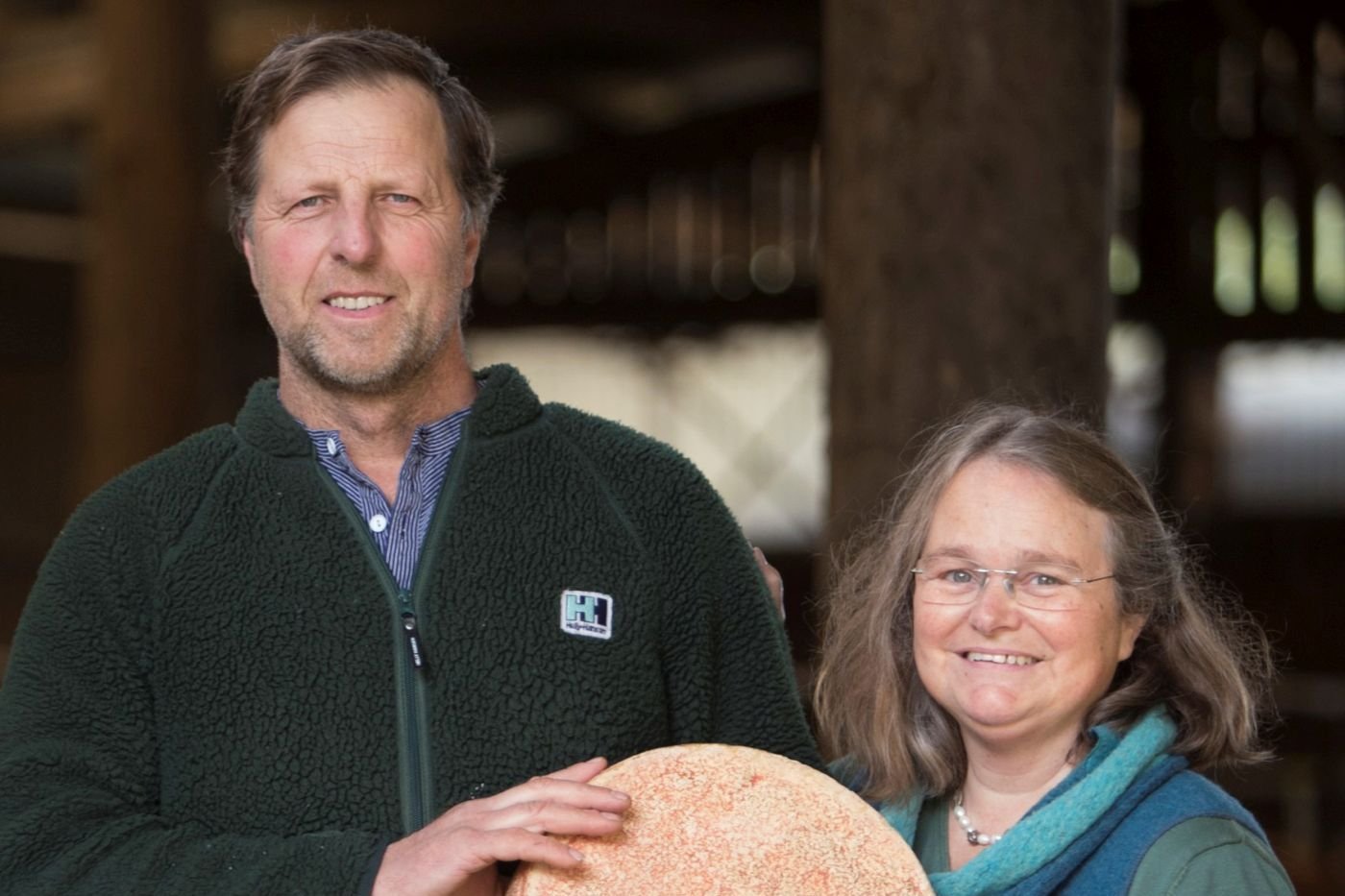 Mann und Frau mit Käselaib. Klick führt zu Großansicht in einer Lightbox. Zum Schließen der Lightbox ESC drücken.