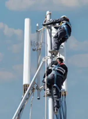 2 techniciens posent un antenne en hauteur sur un toit