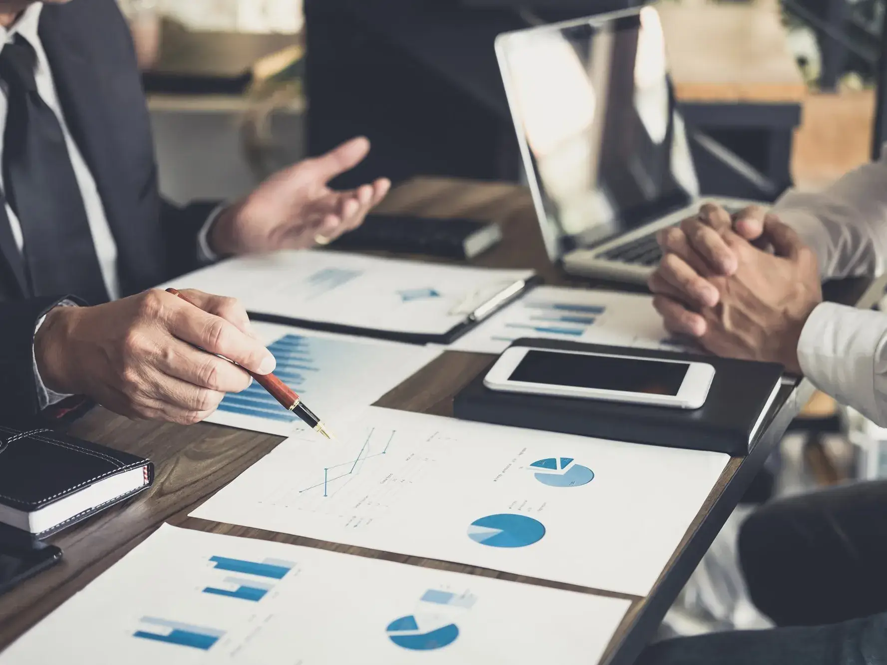 Deux hommes discutent à une table sur laquelle figure des graphiques