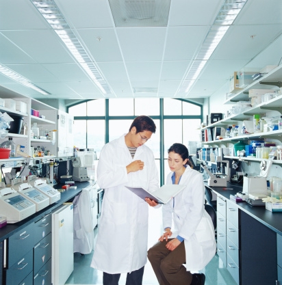 Picture of two researchers, a man and a woman, in a laboratory reviewing a notebook together.